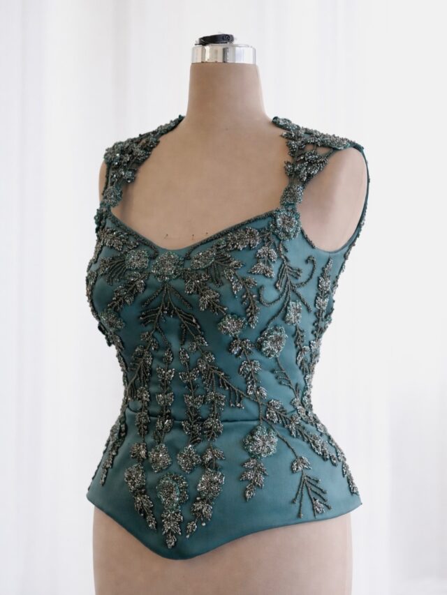 Structured silhouette, a peplum corset, detailed with handsewn embellished flowers.